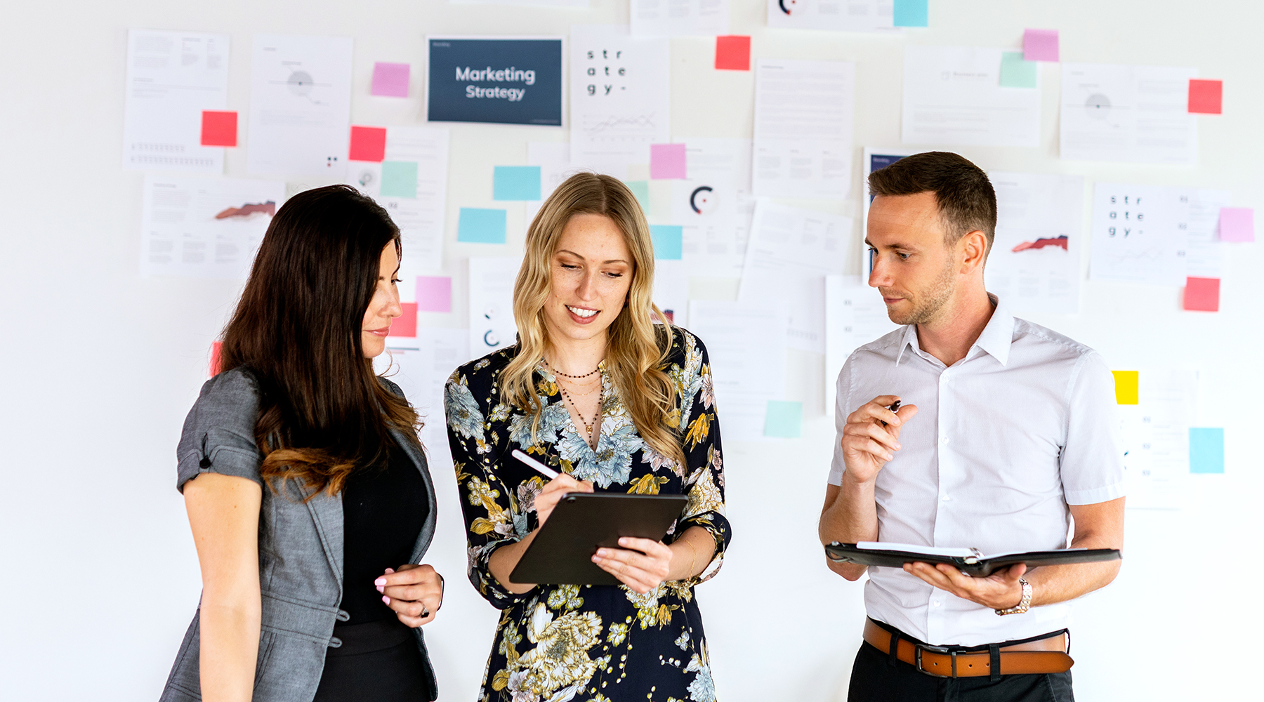 young professionals talking in front of a board of Marketing Strategy notes