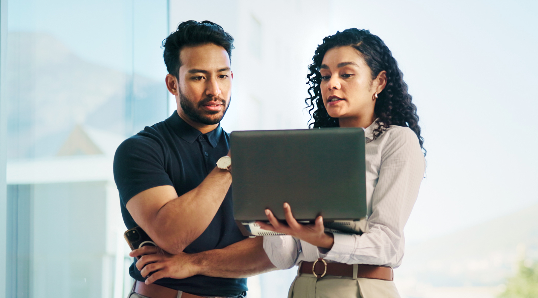 Business man and business woman looking at laptop screen evaluating how to maximize their Microsoft 365 investment